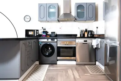 a kitchen with a stove and a washer and dryer at Damac Waves Tower Dubai Marina - By Home Of Choice in Dubai