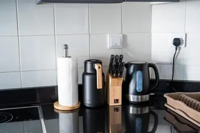 a kitchen counter with two black coffee cups and knives at Damac Waves Tower Dubai Marina - By Home Of Choice in Dubai