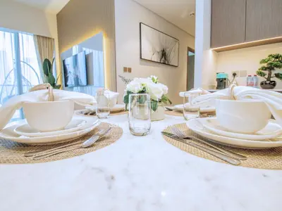 a dining room table with white plates and utensils at GRANDE SIGNATURE- 2BR Apartment with full Burj Khalifa views in Dubai