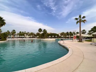 a swimming pool at a resort with palm trees at Keysplease 4BR, Nanny room, BBQ, Garden, Malibu Beach Access, Damac Hills in Dubai