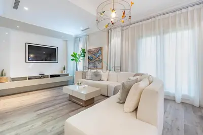 a white living room with a white couch and a tv at Exclusive Beachfront Villa with Private Beach Access, Next to the Community Pool, Close to Aquaventure Waterpark, Monorail, and Nakheel Mall, Canal Cove, Palm Jumeirah by Deluxe Holiday Homes in Dubai