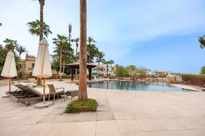 a swimming pool with umbrellas and a table and chairs at Exclusive Beachfront Villa with Private Beach Access, Next to the Community Pool, Close to Aquaventure Waterpark, Monorail, and Nakheel Mall, Canal Cove, Palm Jumeirah by Deluxe Holiday Homes in Dubai