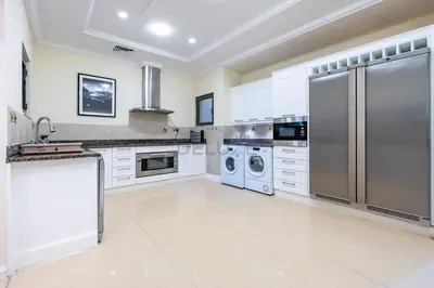 a large kitchen with white cabinets and stainless steel appliances at Exclusive Beachfront Villa with Private Beach Access, Next to the Community Pool, Close to Aquaventure Waterpark, Monorail, and Nakheel Mall, Canal Cove, Palm Jumeirah by Deluxe Holiday Homes in Dubai