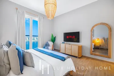 a bedroom with a bed and a tv and a mirror at LUX The La Mer Infinity View - Luxury Boho Suite 1 in Dubai