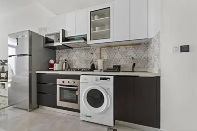 a kitchen with a washing machine and a refrigerator at Stylish Studio Close To Metro at Pearlz by Danube in Dubai