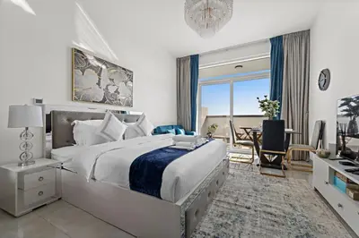 a bedroom with a large bed and a dining room at Stylish Studio Close To Metro at Pearlz by Danube in Dubai