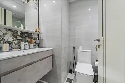 a white bathroom with a toilet and a shower at Stylish Studio Close To Metro at Pearlz by Danube in Dubai