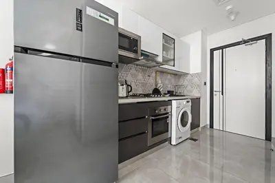 a kitchen with a refrigerator and a washing machine at Stylish Studio Close To Metro at Pearlz by Danube in Dubai
