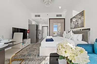 a bedroom with a white bed and a blue couch at Stylish Studio Close To Metro at Pearlz by Danube in Dubai