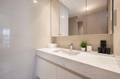 a white bathroom with a sink and a mirror at Full Burj Khalifa View! Brand New 2 Bedrooms! 5min walk From Dubai Mall! in Dubai