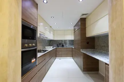 a kitchen with wooden cabinets and a large appliance at Livbnb-2B Stunner with Iconic Ain Dubai View in Dubai