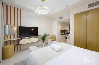 a white bedroom with a large bed and a flat screen tv at Sky-High Aykon City Studio in Dubai
