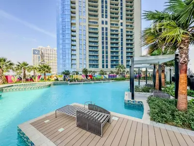 a swimming pool with a bench and palm trees at Sky-High Aykon City Studio in Dubai