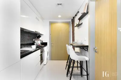 a kitchen with white counters and a yellow door at Sky-High Aykon City Studio in Dubai