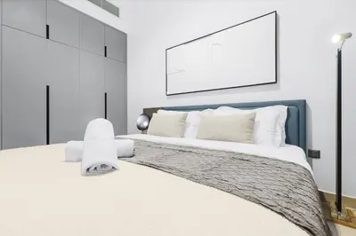 a bedroom with a large white bed with a blue headboard at Luxury 1BR City View with Balcony Parking & WiFi Near Dining & Downtown in Dubai