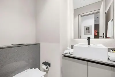 a white bathroom with a sink and a mirror at Luxury 1BR City View with Balcony Parking & WiFi Near Dining & Downtown in Dubai