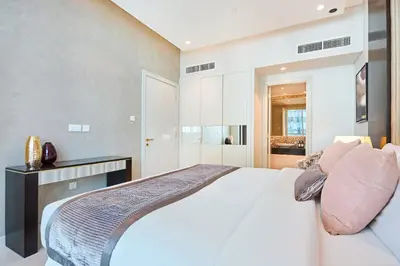 a bedroom with a large white bed with pink pillows at Downtown 1BR - 5 minutes to mall - panoramic pool in Dubai