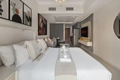 a large white bed in a room with a couch at Modern Studio Apartment in Lake View in Dubai