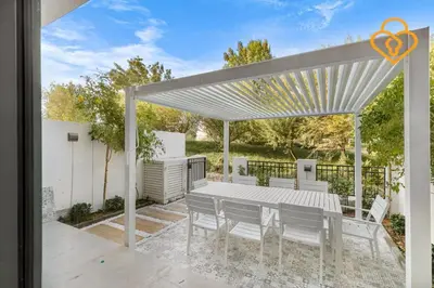 a white pergola with a table and chairs on a patio at Keysplease 4BR, Garden BBQ, Malibu Beach Access, Damac Hills 40 in Dubai