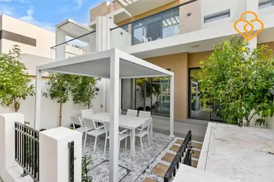 an exterior view of a house with a white table and chairs at Keysplease 4BR, Garden BBQ, Malibu Beach Access, Damac Hills 40 in Dubai
