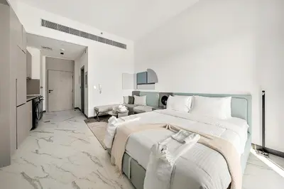 a white bedroom with a large bed and a living room at Bright Studio in MAG Eye in Dubai