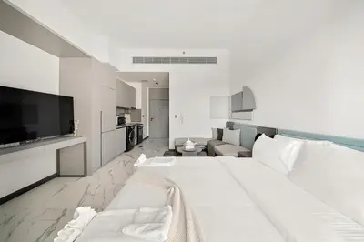 a white bedroom with a large bed and a couch at Bright Studio in MAG Eye in Dubai