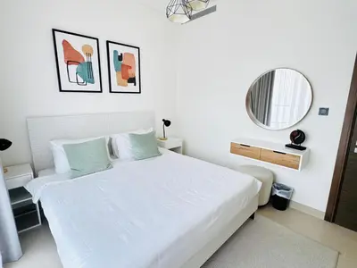 a white bedroom with a white bed and a mirror at Creek Views 1 BR, Mins to Downtown in Sobha Creek Vistas in Dubai