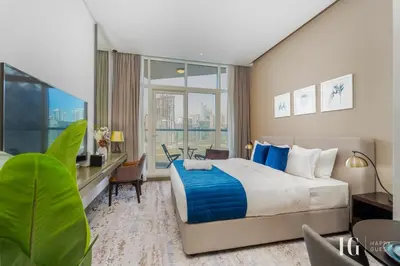a hotel room with a large bed and a desk at Spacious Studio in Damac Maison Prive Canal Views in Dubai