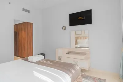 a bedroom with a bed and a tv on the wall at Escape24 Modern 1BR with Pool View in JVC in Dubai