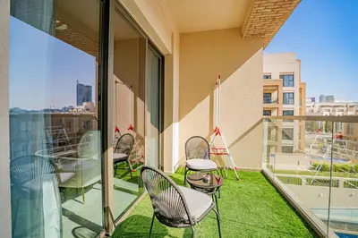 a balcony with chairs and a table on a building at Escape24 Modern 1BR with Pool View in JVC in Dubai