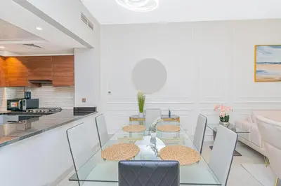 a dining room with a glass table and chairs at Escape24 Modern 1BR with Pool View in JVC in Dubai