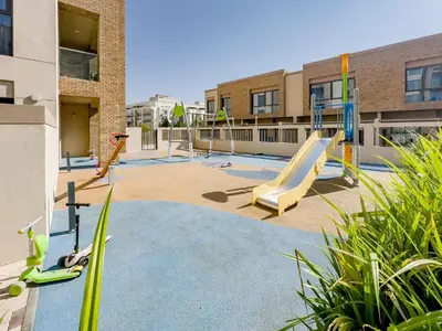 an outdoor playground with a slide and swings at Escape24 Modern 1BR with Pool View in JVC in Dubai