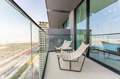 a balcony with two chairs and a table in a building at Delightful 1BR in Binghatti Corner, Jumeirah Village Circle by Deluxe Holiday Homes in Dubai
