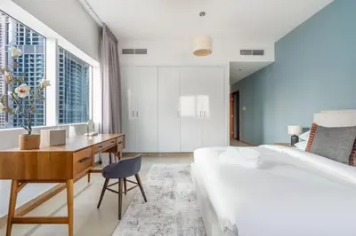 a bedroom with a bed and a desk and windows at GuestReady - Coastal vibes in Dubai Marina in Dubai