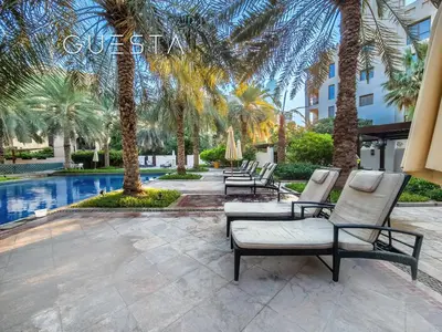 a row of chairs and palm trees next to a pool at Zaafaran 1 by Emaar, Downtown Dubai in Dubai