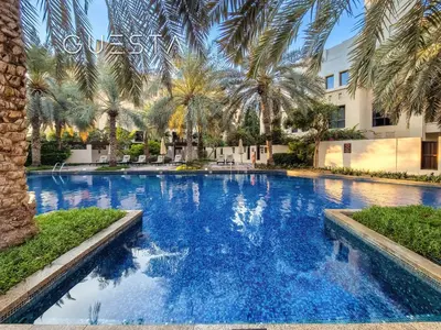 a large swimming pool with palm trees in front of a building at Zaafaran 1 by Emaar, Downtown Dubai in Dubai