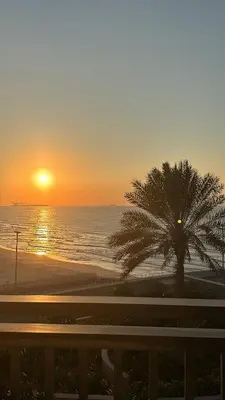 a sunset on the beach with a palm tree at Sea View Luxury 5242 Marina JBR Beach 5mins in Dubai