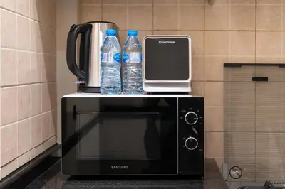 a coffee maker and two bottles of water on top of a microwave at White Sage Incredible Studio Next to Metro in Dubai