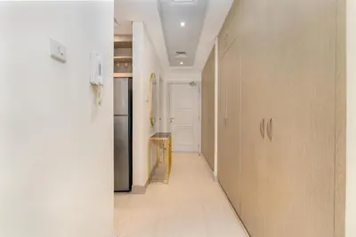 a hallway with wooden cabinets and a refrigerator at White Sage Incredible Studio Next to Metro in Dubai