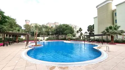 a large pool in a courtyard with chairs and trees at White Sage Incredible Studio Next to Metro in Dubai