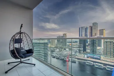 a chair on a balcony with a view of a city at Luxury 2BD Apt with Pool GYM & Burj Khalifa Views in Dubai