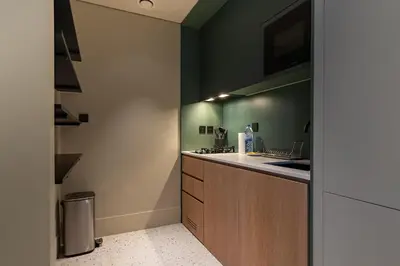 a kitchen with green walls and a counter with a sink at Upside Living Business Bay Stunning Panoramic Burj Cityline Views by Simply Comfort in Dubai
