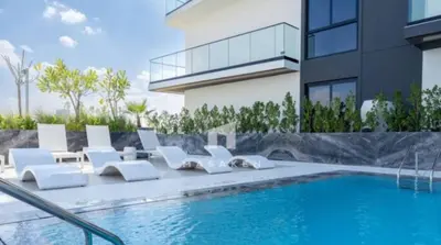 a swimming pool with white lounge chairs next to a building at Chic Jvc 1br Balcony, Pool And Parking in Dubai