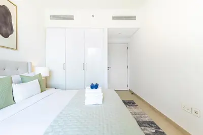 a white bedroom with a white bed with blue pillows at Premium 3BR l Office with Burj Khalifa & Fountain Views in Dubai