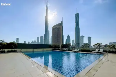 a swimming pool with a city skyline in the background at bnbme - Luxury 4BR Downtown Views II Apt Burj Khalifa Views Pool Gym Parking in Dubai