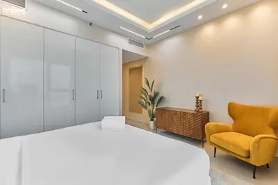 a bedroom with a large bed and a yellow chair at bnbme - Luxury 4BR Downtown Views II Apt Burj Khalifa Views Pool Gym Parking in Dubai