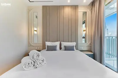 a bedroom with a large white bed and a balcony at bnbme - Luxury 4BR Downtown Views II Apt Burj Khalifa Views Pool Gym Parking in Dubai