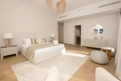 a white bedroom with a bed and a mirror at HiGuests - Experience Coastal Elegance at La Rive 2 in La Mer in Dubai