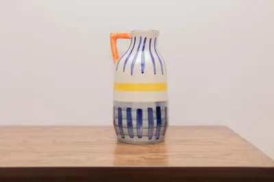 a striped vase sitting on a wooden table at HiGuests - Experience Coastal Elegance at La Rive 2 in La Mer in Dubai