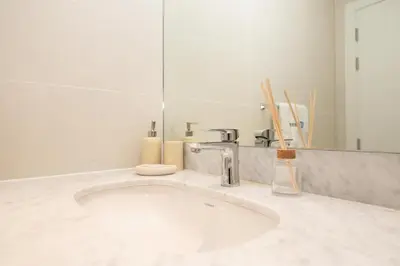 a white bathroom with a sink and a mirror at HiGuests - Experience Coastal Elegance at La Rive 2 in La Mer in Dubai